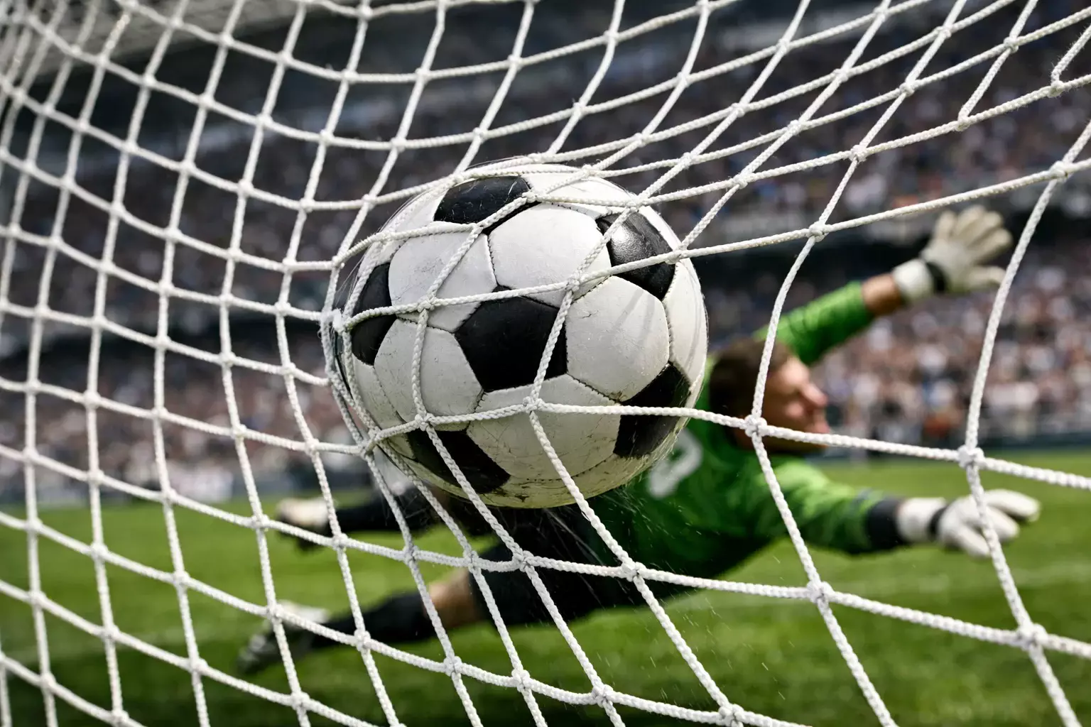 Balón de fútbol entrando en la portería visto desde detrás de la red